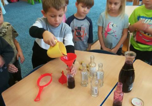 Chłopiec nalewa sok do buteleczek.